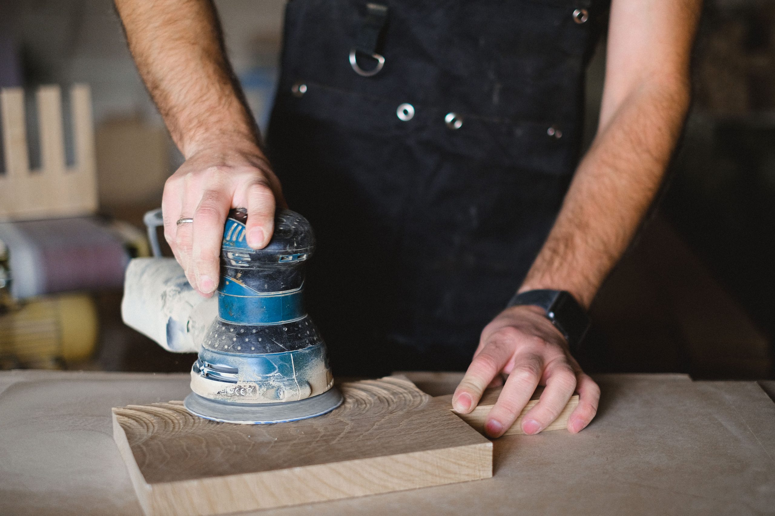 Menuisier utilisant ponceuse orbitale sur détail bois