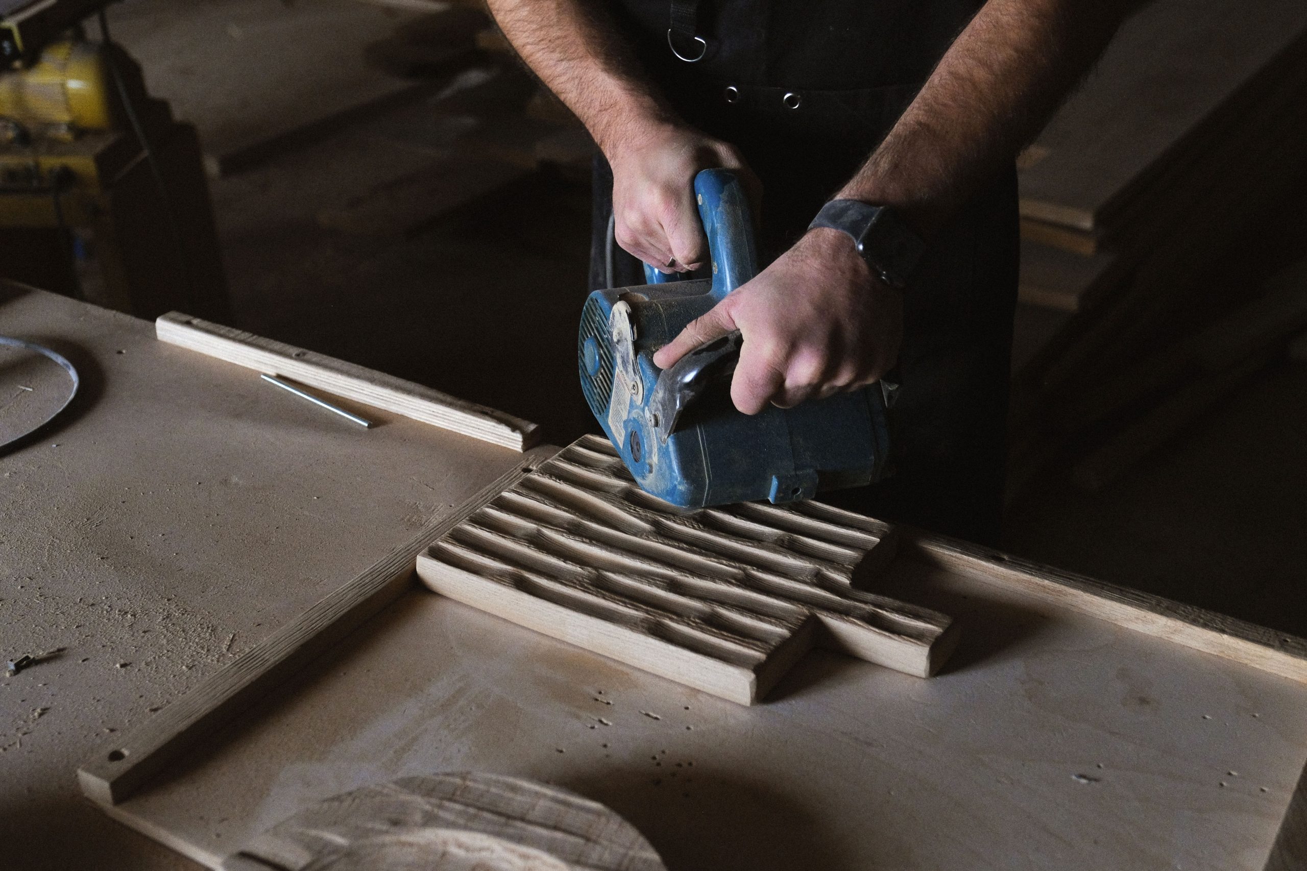 Menuisier ponçant planche bois avec outil électrique