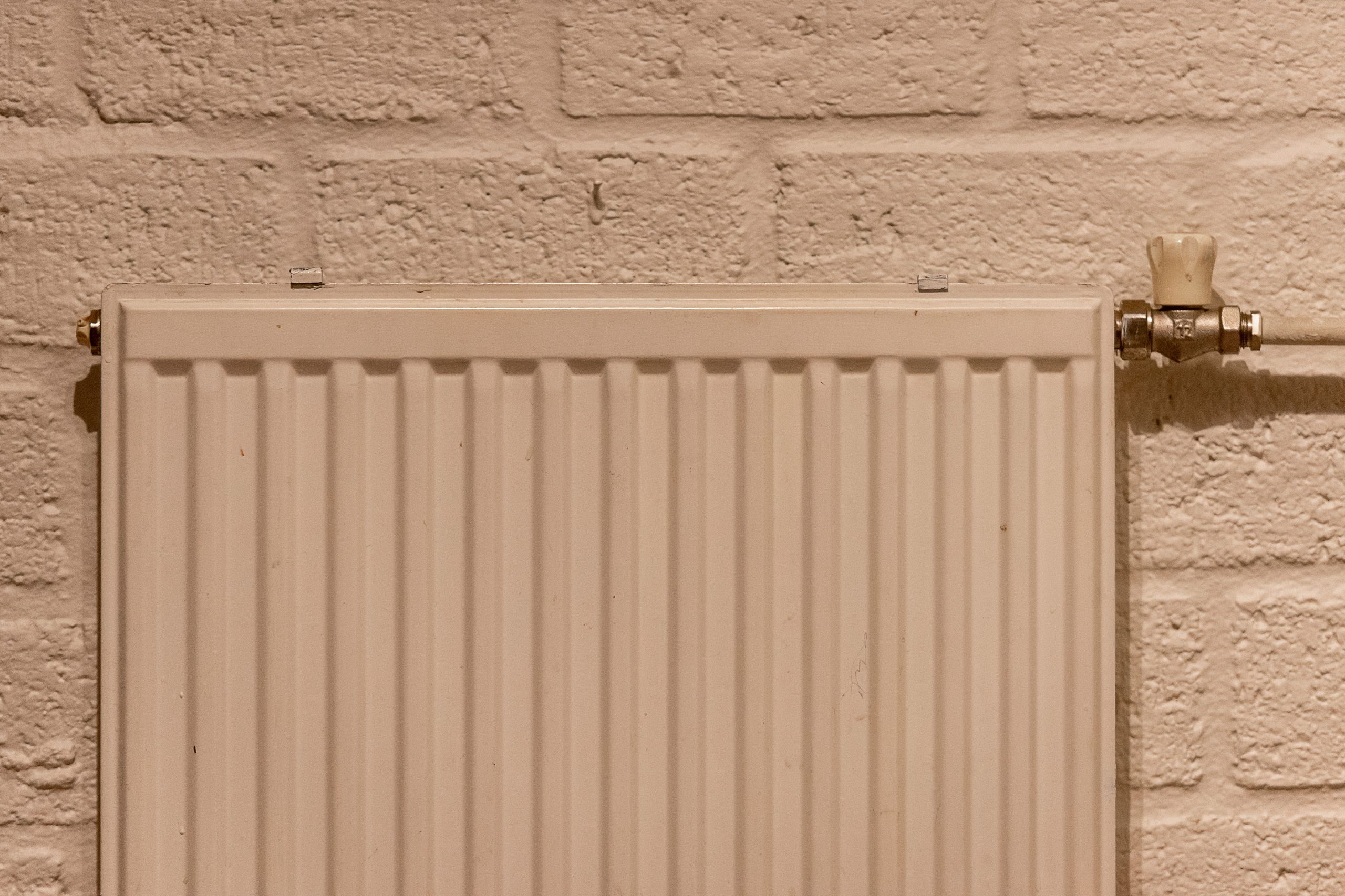 Radiateur blanc propre sur mur en briques